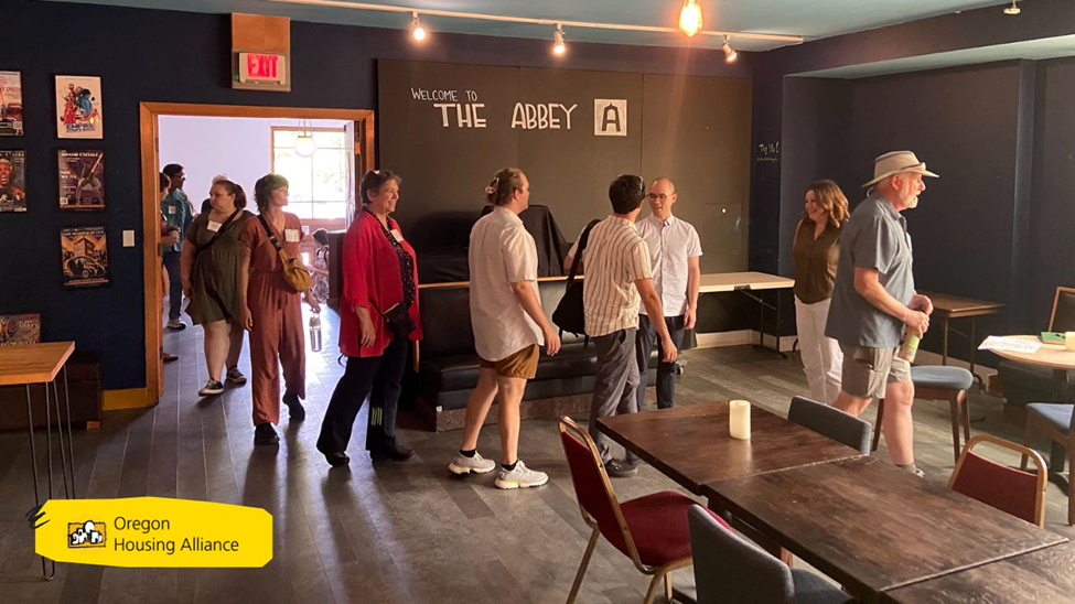 line of people walking into a room with black walls being greeted as they enter